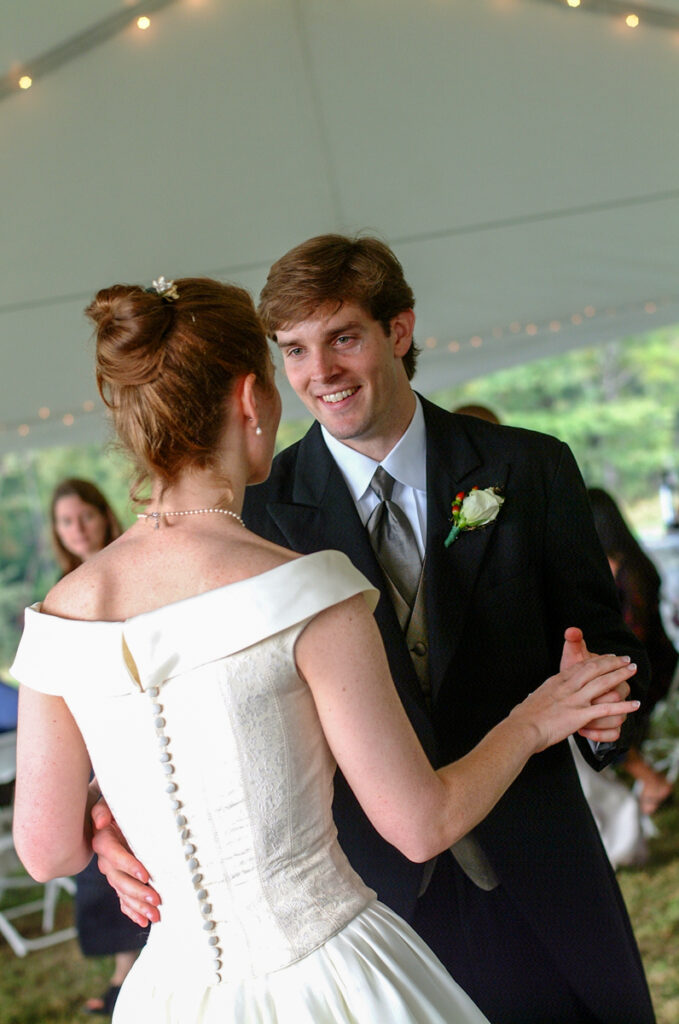 The couple’s first dance under the tent, the groom looking at the bride.