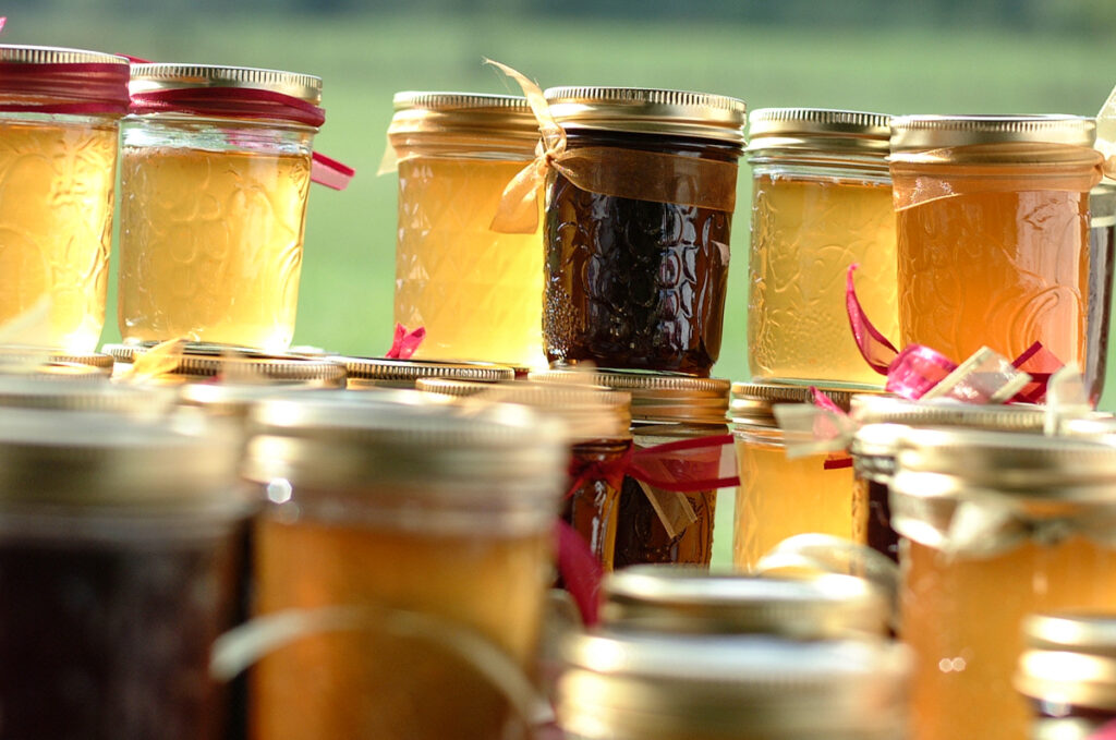 : Backlit jars of homemade jelly favors glowing in late-day sun
