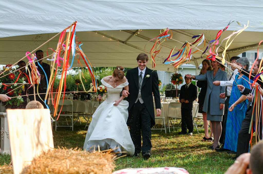 Guests wave ribbon wands as the newlyweds walk out through a tunnel of color.